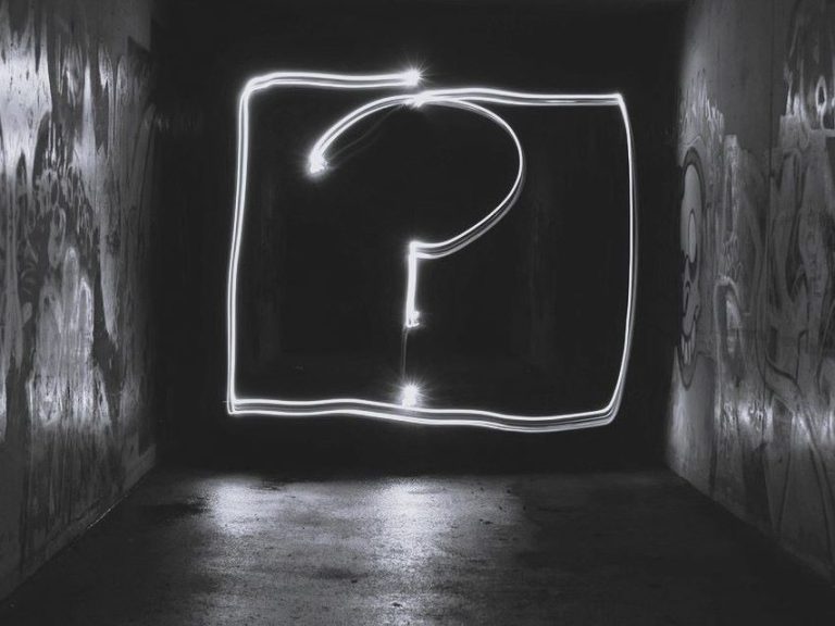Ein leuchtendes Fragezeichen in einem dunklen, graffitibeschmierten Tunnel.