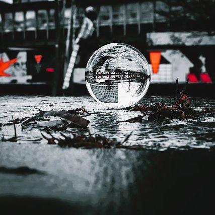 Kugel auf einem Boden, reflektiert Umgebung mit Gedöns und Unschärfe.