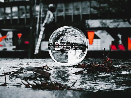 Eine reflektierende Glaskugel auf einem schmutzigen Boden mit verschwommenem Hintergrund.