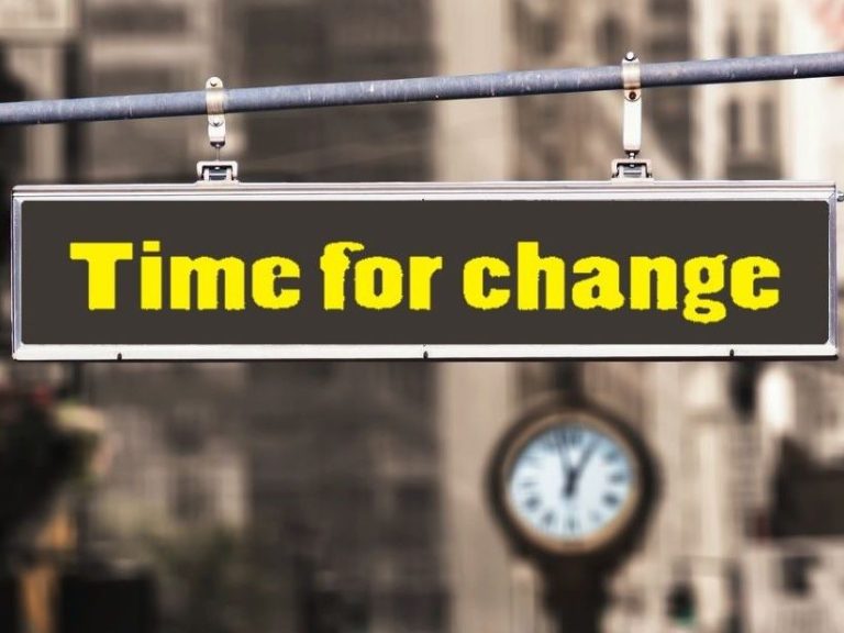 Schild mit der Aufschrift "Time for change" und einer Uhr im Hintergrund.