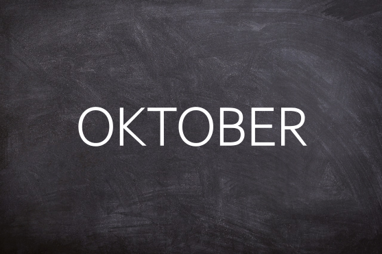 Oktober Schwarze Tafel mit dem Wort "OKTOBER" in großen, weißen Buchstaben.